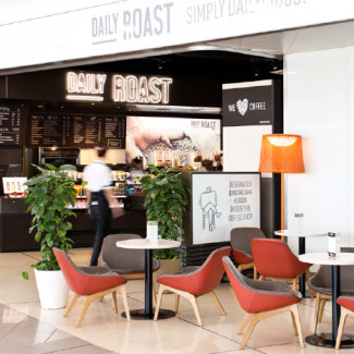 Sitzbereich im Café Daily Roast mit roten Stühlen und Blick zur Theke.