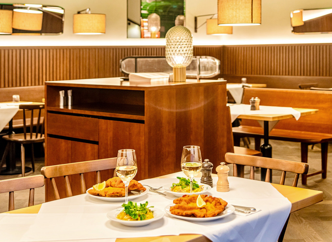 Ein gedeckter Tisch mit zwei Wiener Schnitzel inkl. Kartoffelsalat und Wein im Figlmüller Bäckerstraße.