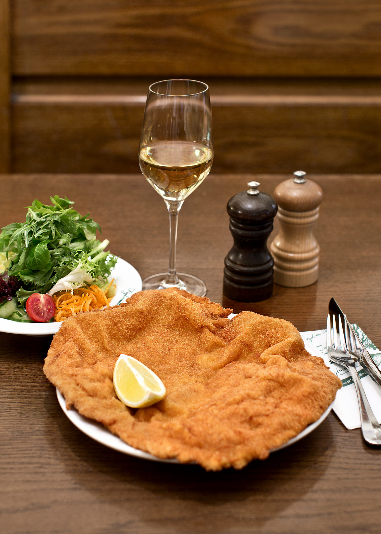 Das originale Figlmüller Wiener Schnitzel - serviert mit Zitrone und Salat.